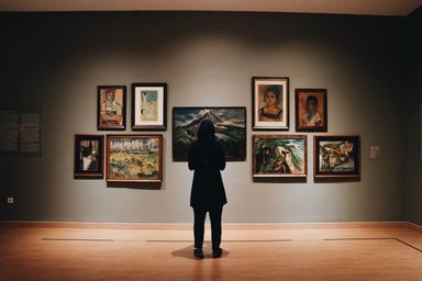 A woman in a black coat standing in front of paintings